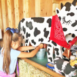 young girl milking wooden cow